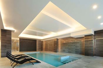 A modern indoor swimming pool with a glass wall and a wooden partition.